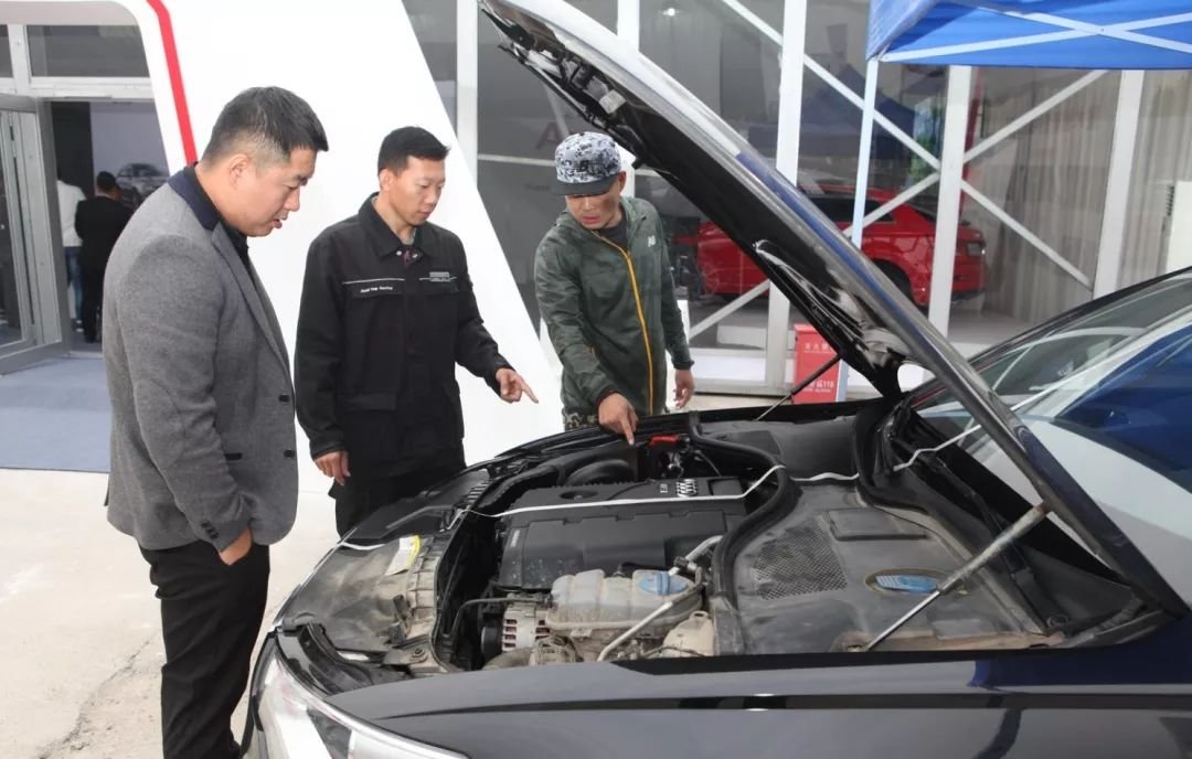 Certified mechanics performing pre-export used car inspection at warehouse